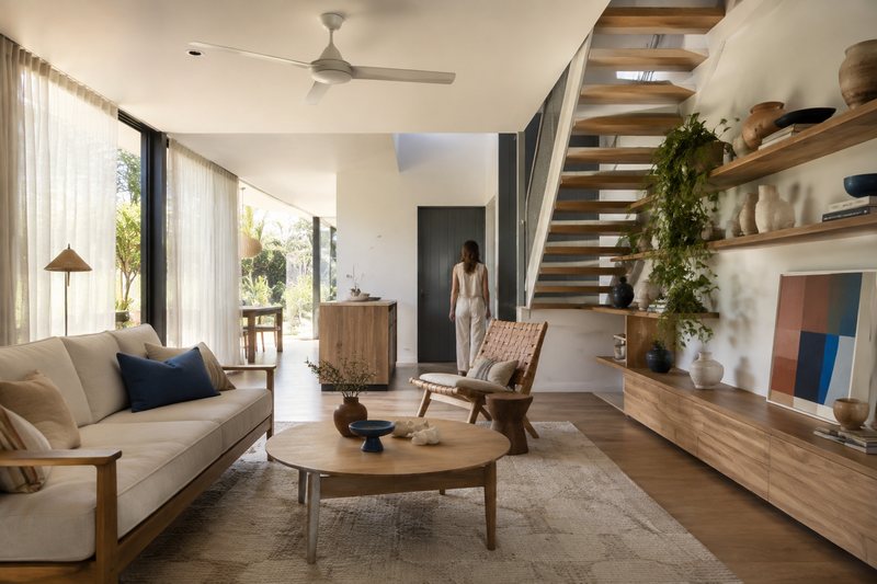 A sunlit Brisbane living room with timber furniture, linen upholstery and open shelving